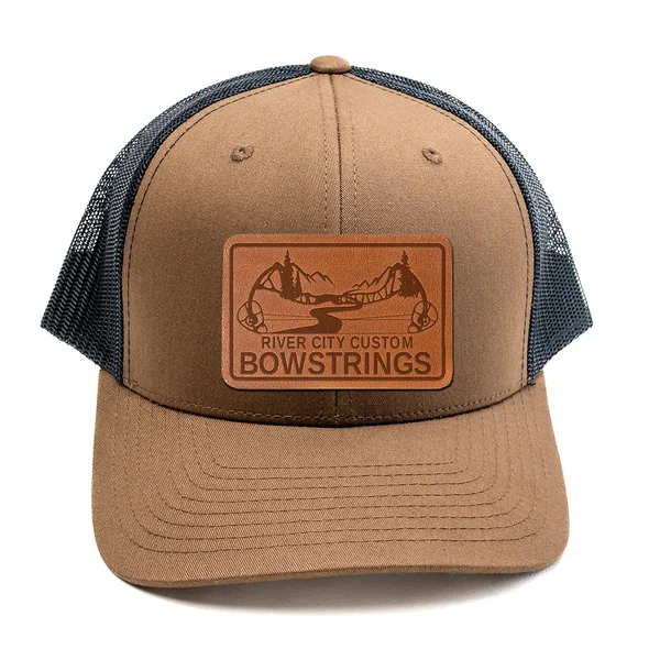 River City Custom Bowstrings trucker cap, tan crown with a charcoal mesh back and a leather patch of the bow mark